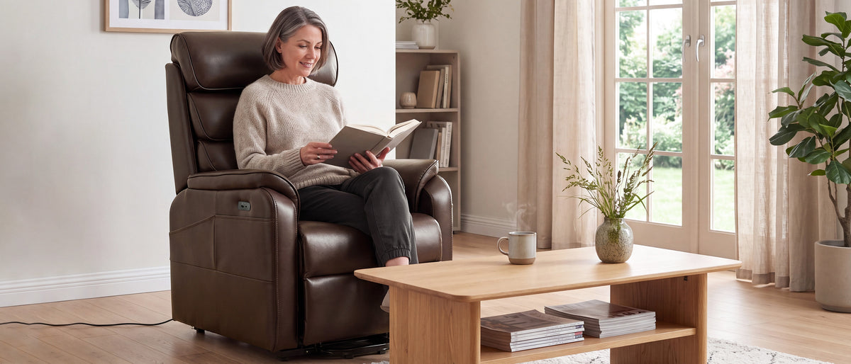A woman sitting and reading in the Irene House 9188S Pro in brown breathable faux leather beside a sunlit window