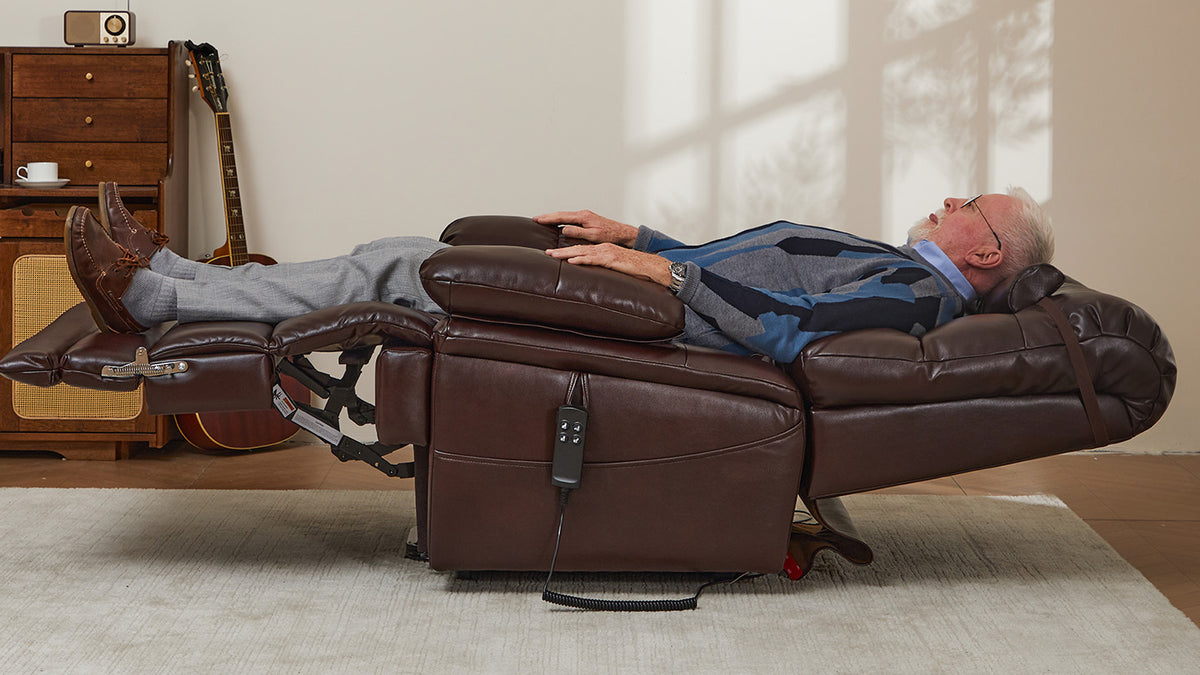 A man lying fully flat in an Irene House 9205L brown lift recliner holding the hand control, repositioning without getting up