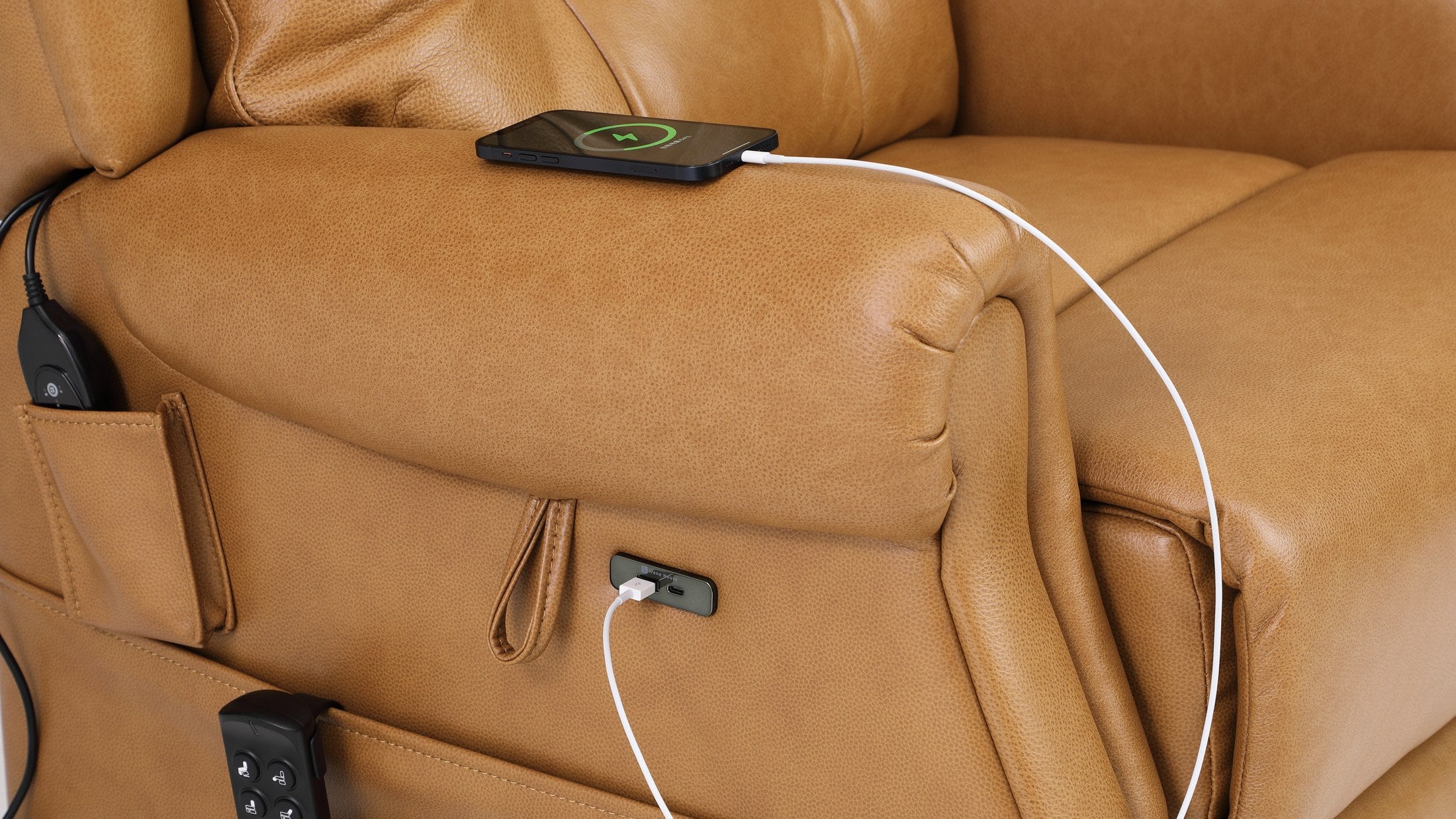 A phone charging from the USB port in the side panel of the Irene House 9199 camel top grain leather recliner