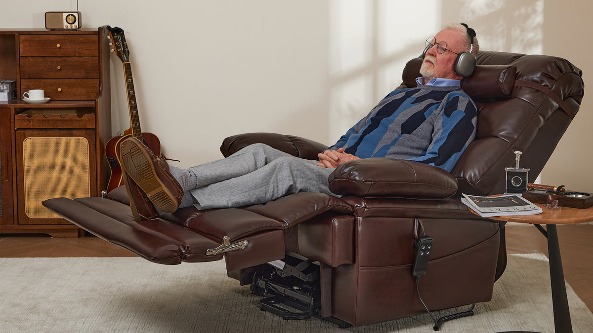 A tall man reclined in an Irene House lift recliner with his legs fully supported on the extended footrest, head resting against a tall backrest