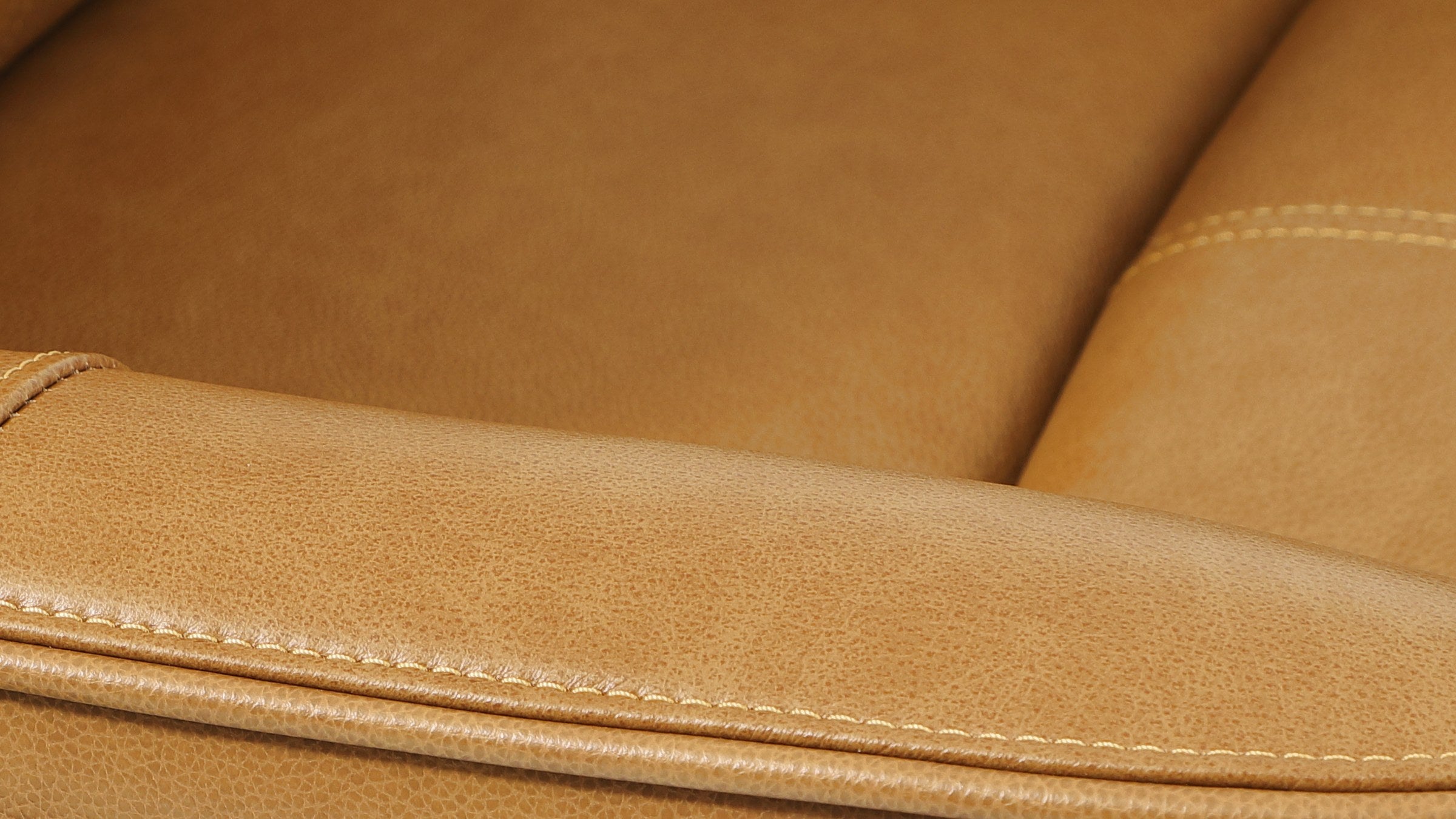 Close-up of the camel brown top grain leather on the Irene House 9219, showing the natural grain and the contrast stitching along the arm