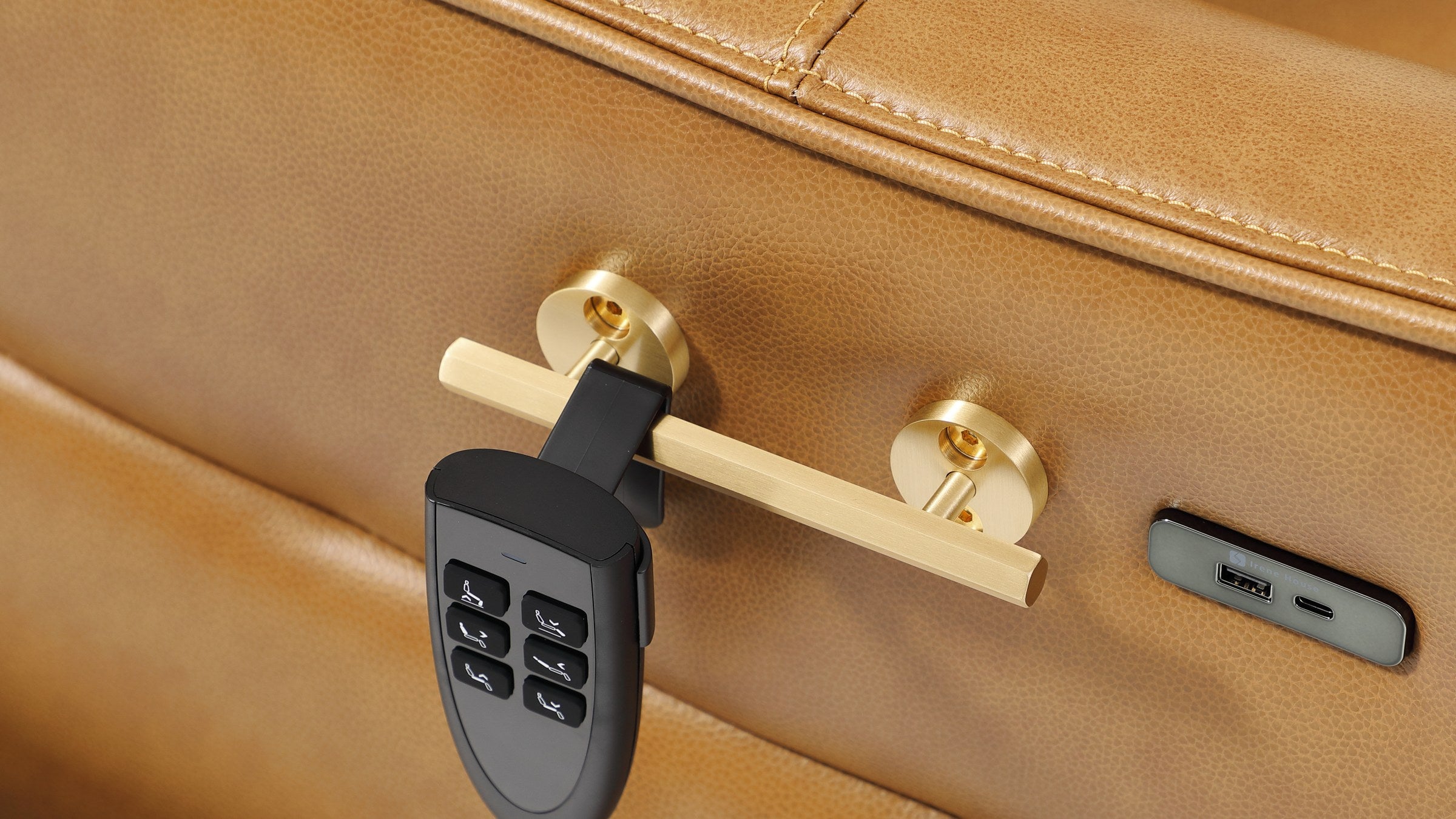Solid brass rail on the side panel of the Irene House 9219 camel brown recliner with the six-button hand control clipped onto it, and the USB-A and USB-C charging plate alongside