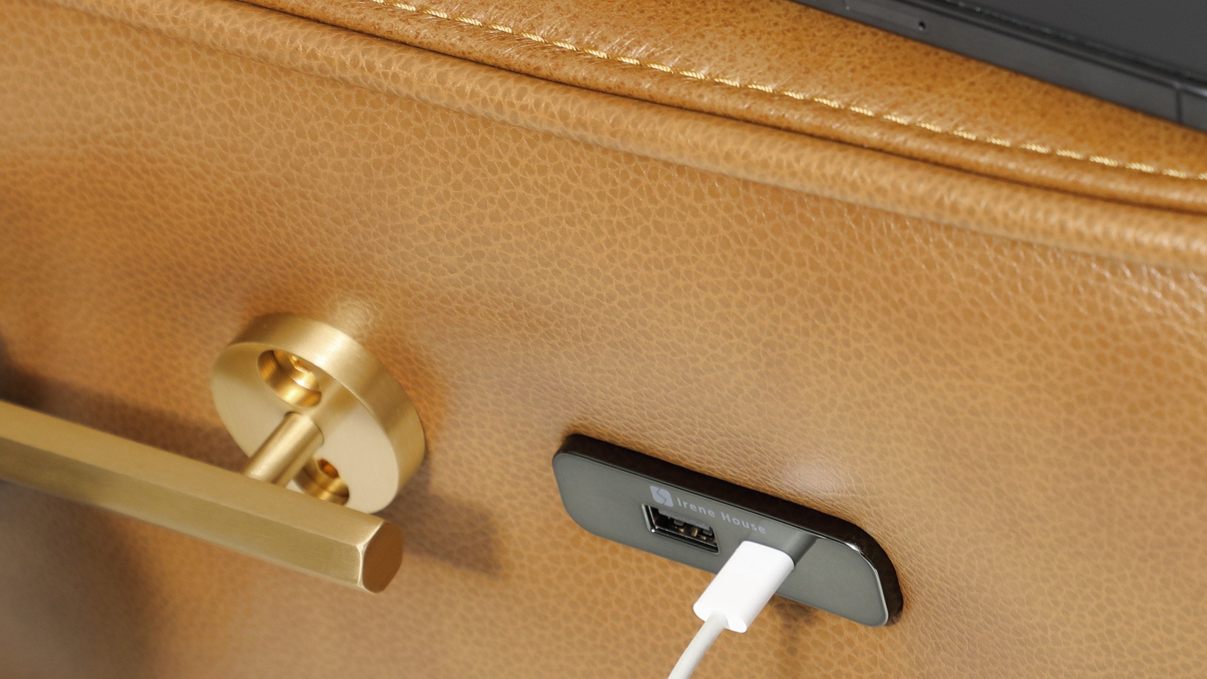 Charging cable plugged into the USB-A port on the Irene House 9219 side panel, next to the solid brass rail